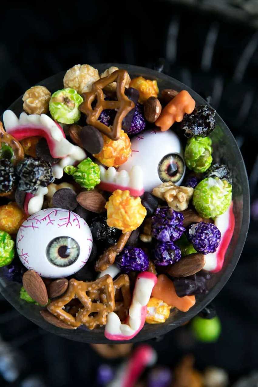 Bowl of mixed pretzels, popcorn, candy corn, and orange M&Ms shaped like a monster mash